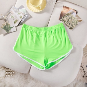 Neon green yoga shorts with white contrast trim and elastic waistband on a table