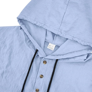 Macro detail of men's light blue linen hoodie shirt showing fabric texture and hoodie strings