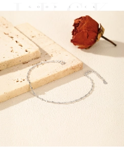 Detail of S925 sterling silver beaded chain bracelet on a textured stone with a dry rose