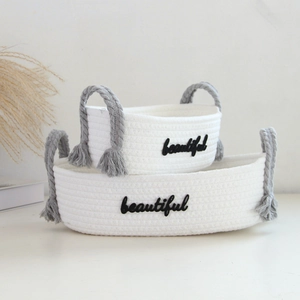 Nesting white cotton rope storage baskets with gray fringe handles and cursive text