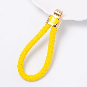 Detail view of a yellow braided leather keychain with golden metal clasp and heart charm