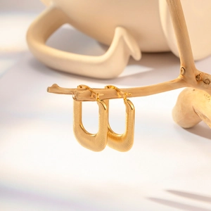 Détail de boucles d'oreilles en U plaquées or 18 carats avec texture métallique nervurée