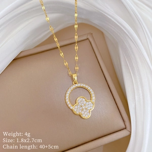 Close-up of gold clover pendant with crystals and jewelry specifications on beige background