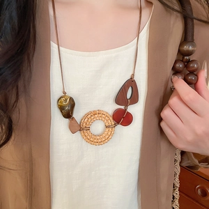Close-up of bohemian pendant with woven rattan, wood, and resin on a brown cord