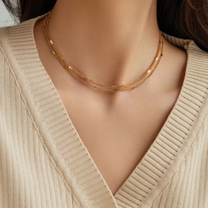 Elegant 18K gold-plated triple-layer titanium steel necklace on a chic V-neck sweater
