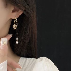 Détail de boucles d'oreilles tulipe avec pampilles dorées et perle sur un mannequin