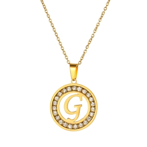Detailed close-up of a gold-plated necklace featuring a round pendant with letter G and crystals