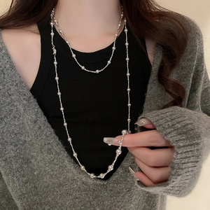 Détail du long collier de perles argentées à plusieurs rangs porté par un mannequin