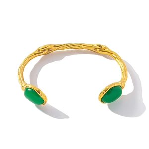 Macro view of gold plated branch texture cuff with two oval green natural stones