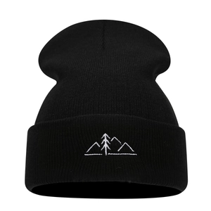 Black knit beanie featuring minimalist white mountain and pine tree embroidery on the cuff