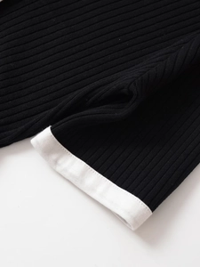 Dettaglio macro dell'abito in maglia a coste nero con bordo bianco a contrasto