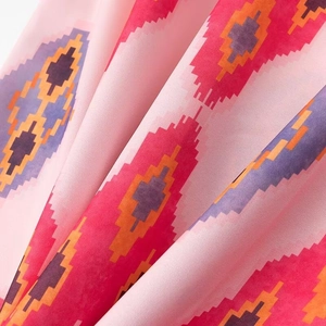 Close-up of pink ethnic ikat print fabric with red and purple geometric patterns