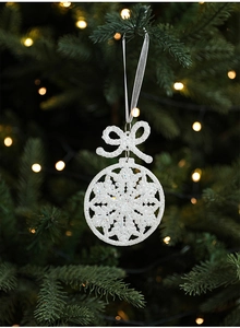 Close-up of white glitter snowflake ornament with silver ribbon on a green Christmas tree