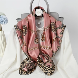 Detail of pink silk scarf featuring golden chains and leopard patterns tied on display