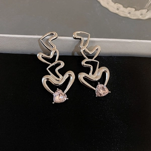 Macro shot of silver-colored layered heart earrings with pink heart zircon stones