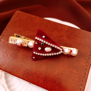 Detail of red velvet triangle hair clip with festive pearls and rhinestones on gold base