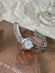 Detail of silver fishbone bracelet watch with mother of pearl dial and crystal accents