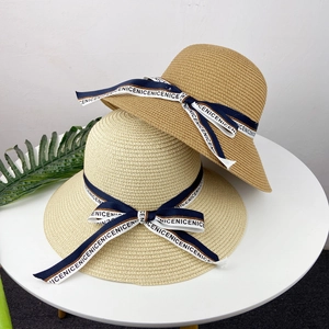 Détail de chapeaux de paille en beige et marron clair avec rubans bleu marine lettrés
