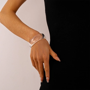 Dicker Armreif aus klarem Acryl in geometrischem Design am Handgelenk eines Models