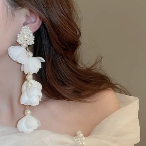 Detailed close-up of white chiffon flower drop earrings with elegant pearl accents