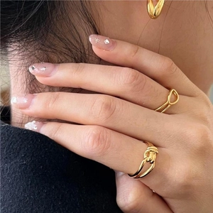 Detail view of gold knot ring and teardrop earrings set on a female model