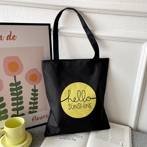 Detail of black oxford tote bag with yellow hello SUNSHINE print in a lifestyle setting