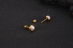 Close-up of minimalist gold pearl stud earring showing fine metal texture and backing
