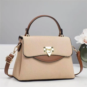Detail of khaki canvas tote with brown leather trim and golden metal lock closure