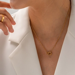 Elegante goldene Halskette mit zwei ineinandergreifenden Ringen an Modell in Blazer