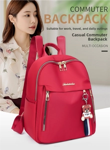 Detail of red water-resistant nylon backpack featuring gold zippers and a bear pendant