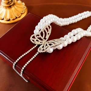 Detail of double-layer pearl necklace with a sparkling butterfly pendant on jewelry box