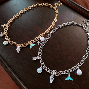 Detailed view of nautical necklaces featuring golden shells and fish tail charms