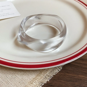 Detailed close-up of a clear acrylic twisted bangle displayed on a ceramic dish