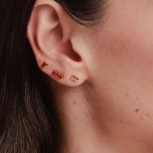 Close-up of S925 silver stud earrings with red and pink rectangular zircons on ear