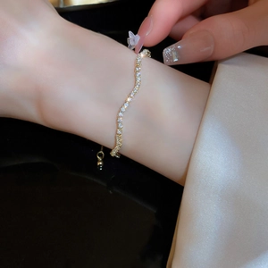 Macro shot of wavy gold bracelet with pave diamonds on woman wrist and silk