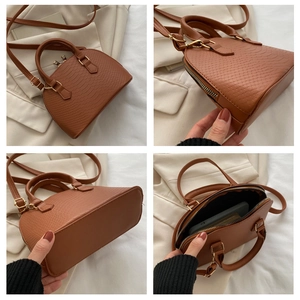 Detail showing brown crocodile texture, zipper, base and interior of shell handbag