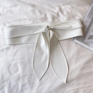 Détail d'une ceinture large en cuir PU blanc avec nœud papillon sur tissu texturé