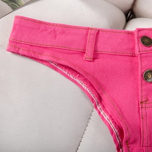 Gros plan détaillé sur un denim rose vif avec des coutures contrastées et un bouton en métal