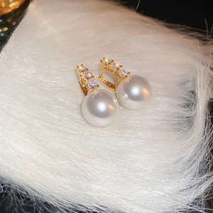 Vue détaillée des boucles d'oreilles perles en métal doré et pierres de zircone