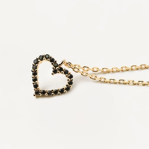 Macro shot of gold-plated chain and hollow heart pendant with black gemstones