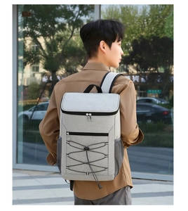 Gray insulated picnic backpack with reflective strips and bungee net shown on a model