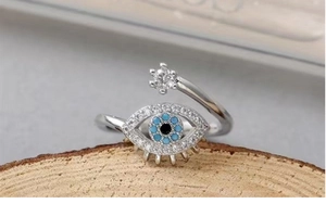 Macro detail of Evil Eye ring with blue crystal and star on a rustic wood stand