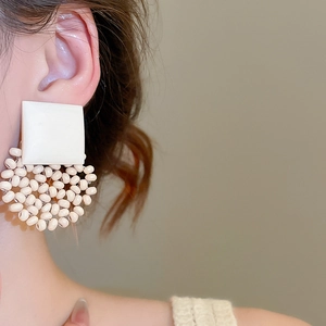 Close-up of geometric vintage earrings with white square stud and circular beaded cluster