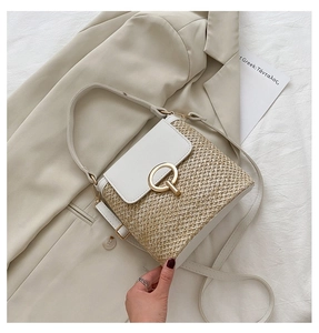 Detail of a straw crossbody bucket bag with white leather flap and gold metal ring buckle