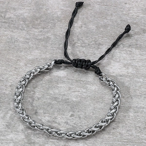 Close-up of silver wheat chain bracelet with adjustable black drawstring and knot closure