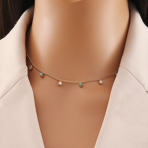 Detail of gold chain necklace featuring turquoise beads and clear teardrop gemstones