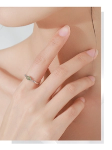 Gros plan d'une bague en argent sertie d'une pierre précieuse vert clair sur un doigt