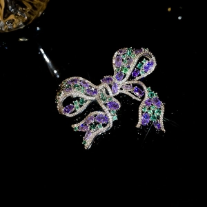 Detailed macro shot of sparkling zircon bow brooch with purple and green gemstones