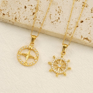 Golden nautical compass and ship wheel necklaces with sparkling zircon stones on stone