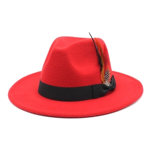 Detailed macro view of red wool felt hat featuring a black ribbon bow and colorful feather